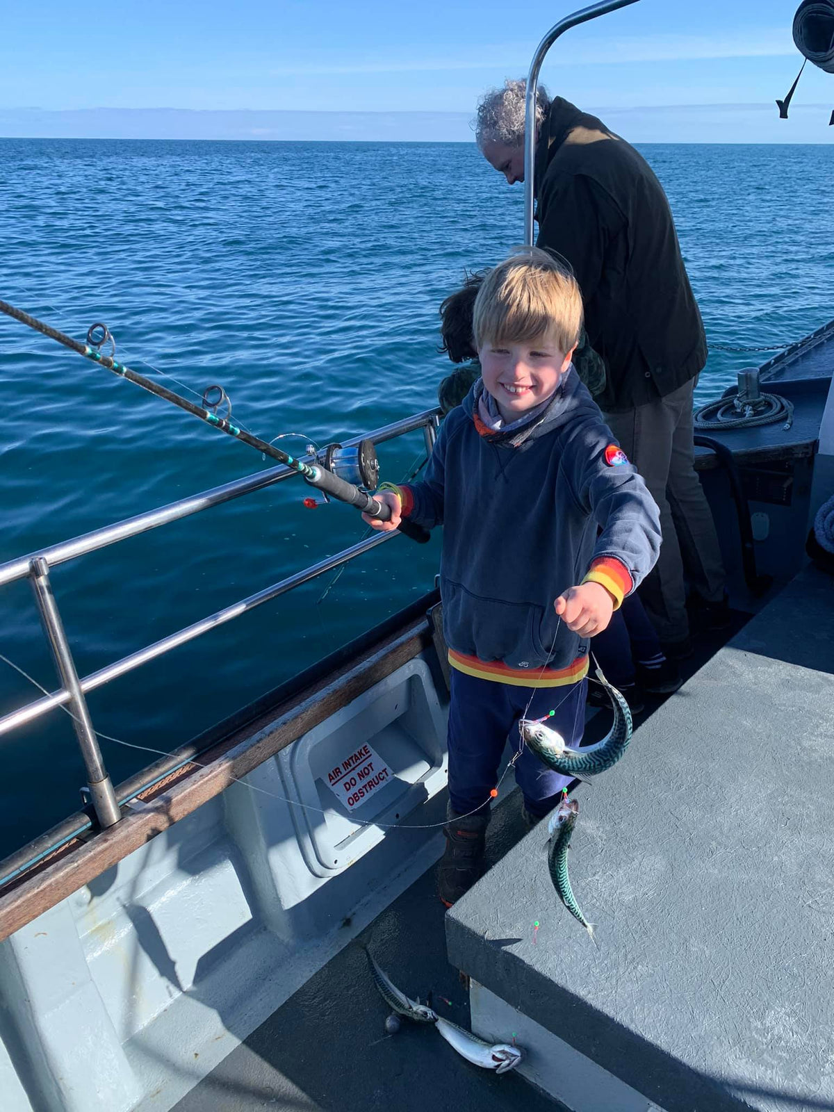 Child holding a fish during a family fishing trip from Padstow